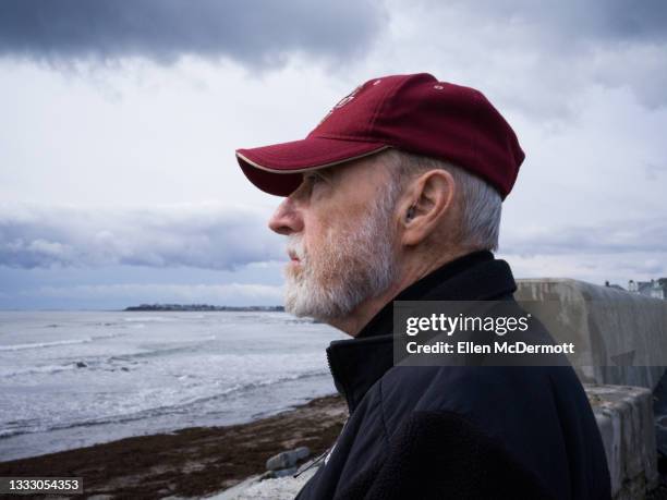 senior male at beach in winter - ellen mann stock-fotos und bilder