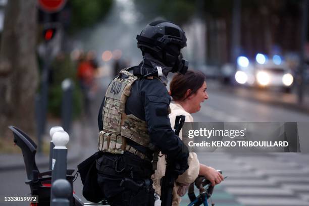 Police officer of unit RAID helps a passer by to cross the street during protests in Lille, northern France, on June 29 two days after a teenager was...
