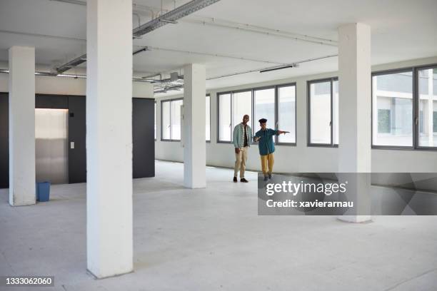 commercial real estate agent showing office space to client - real estate office stockfoto's en -beelden
