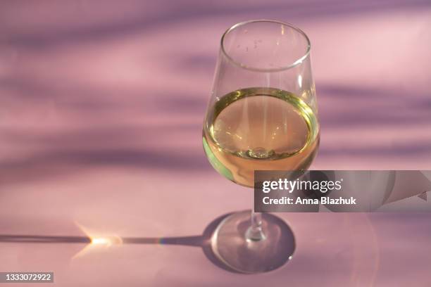 glass of white wine in bright sunlight with shadows and reflections over pink background. - bottle champagne from above stock pictures, royalty-free photos & images