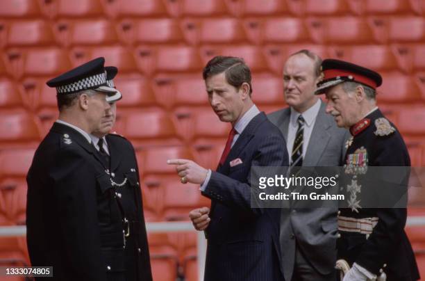 British Royal Charles, Prince of Wales, speaking with unspecified police officers during a visit to Anfield, the home of Liverpool Football Club, to...
