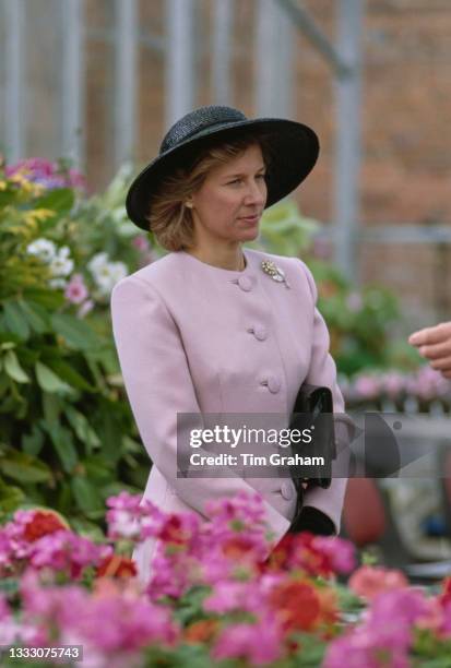 Danish member of the British Royal Family Birgitte, Duchess of Gloucester, wearing a pale pink outfit and a black wide-brim hat, in the greenhouse...