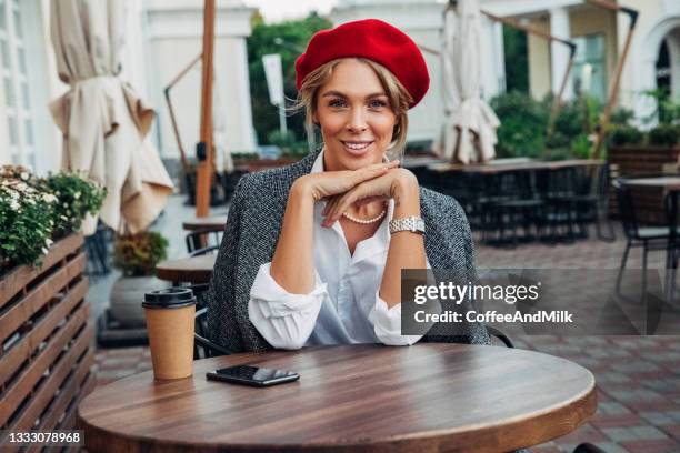 beautiful woman wearing red beret drinking coffee - french women stock pictures, royalty-free photos & images