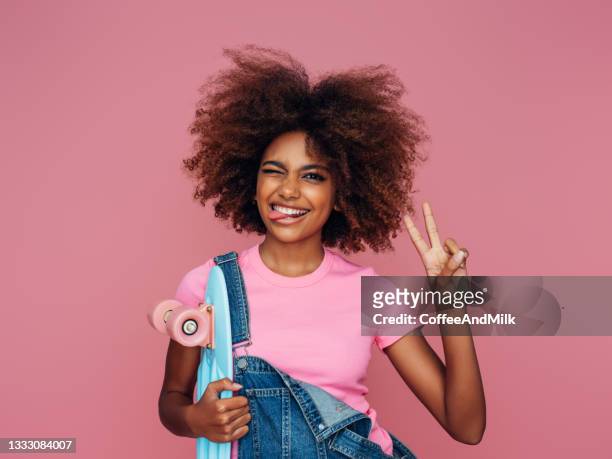foto von jungem lockigem mädchen mit skateboard - afro frisur stock-fotos und bilder