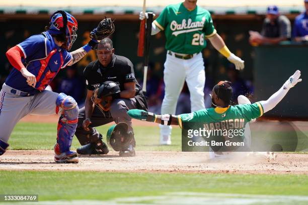 Josh Harrison of the Oakland Athletics slides safely past Jonah Heim of the Texas Rangers into home plate during the first inning at RingCentral...