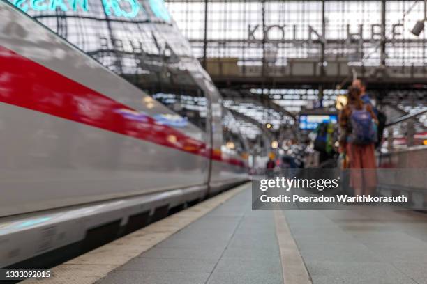 selective focus at platform of cologne central railway station with blur background of motion of high speed train and group of passengers in cologne, germany. - passenger train stock pictures, royalty-free photos & images