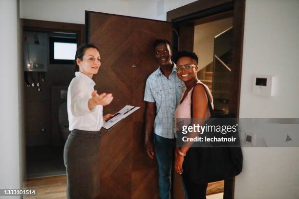 real estate agent greeting the young couple at the new apartment - search new home stock pictures, royalty-free photos & images