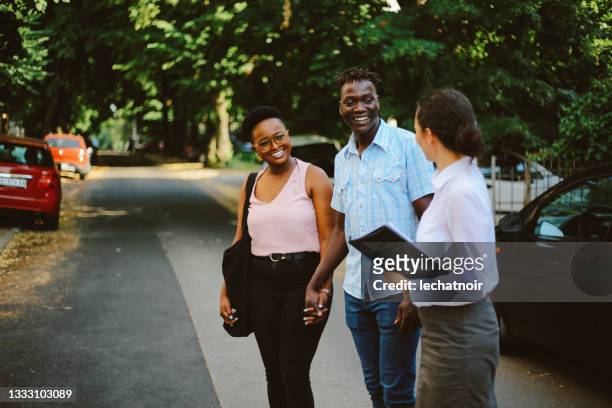 young couple meeting with the real estate agent to look at the new apartment - search new home stock pictures, royalty-free photos & images