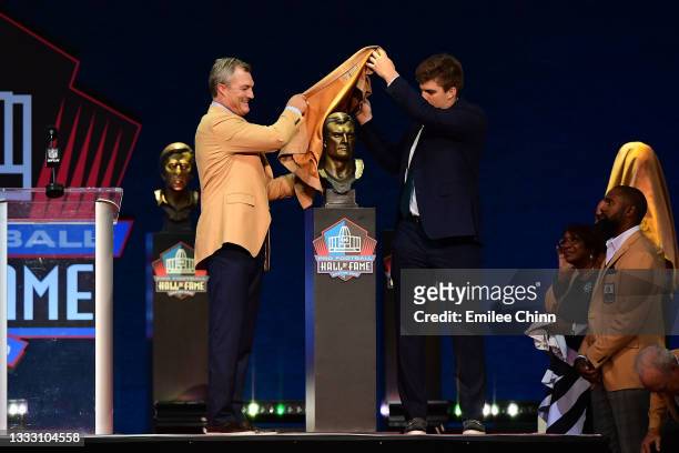 John Lynch unveils his bust with his son Jake Lynch during the NFL Hall of Fame Enshrinement Ceremony at Tom Benson Hall Of Fame Stadium on August...