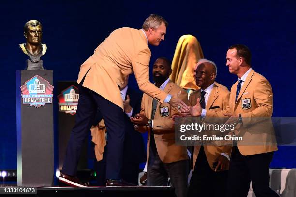 John Lynch shakes hands with Peyton Manning during the NFL Hall of Fame Enshrinement Ceremony at Tom Benson Hall Of Fame Stadium on August 08, 2021...