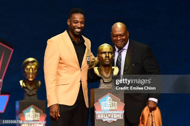 Calvin Johnson and Derrick Moore pose with Johnson's bust during the NFL Hall of Fame Enshrinement Ceremony at Tom Benson Hall Of Fame Stadium on...