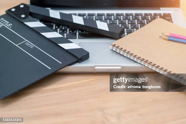 video editing,movie clapper laptop and pencil notepad on the wood table top view shot. - scenario stockfoto's en -beelden