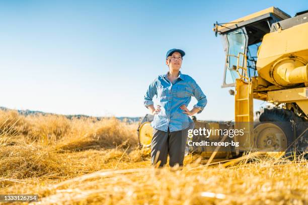 porträt der jungen bäuerin mit mähdreschermaschine auf dem feld - farmer female confident stock-fotos und bilder