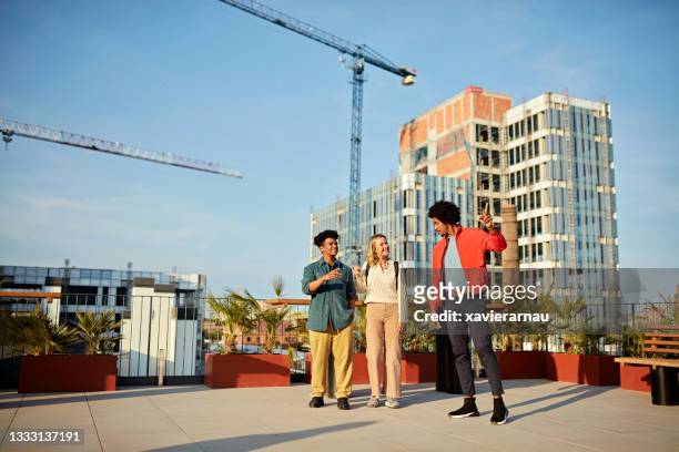 commercial real estate agent showing clients rooftop deck - commercial real estate agent stock pictures, royalty-free photos & images