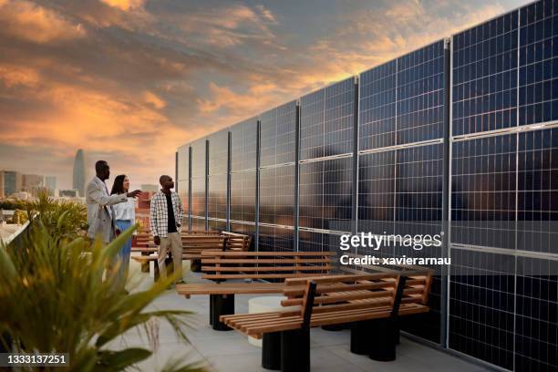 makler und kaufinteressenten bewundern solarenergiesystem - roofing stock-fotos und bilder