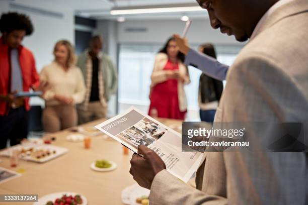 black male real estate agent looking at flyer for commercial property - flyers business people bildbanksfoton och bilder