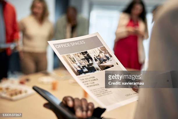 black real estate agent reading flyer for commercial property - flyer stockfoto's en -beelden