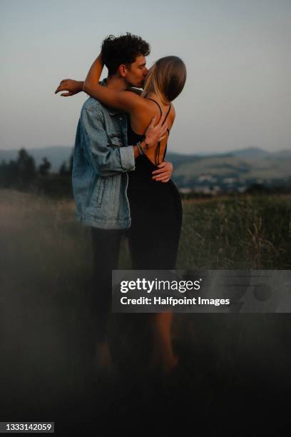 portrait of young couple standing, hugging and kissing outdoors. - young couple kiss ストックフォトと画像