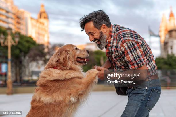 mature man hugging with his golden retriever dog - golden retriever stock pictures, royalty-free photos & images