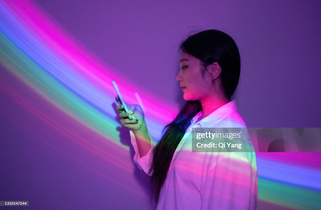 Young Asian woman using smartphone on rainbow background