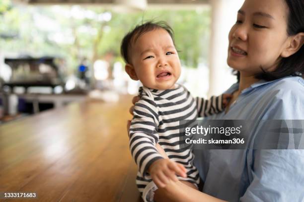 asian female daughter feeling negative emotion and  crying and shouting  with her mother embracing - spilt milk stock-fotos und bilder