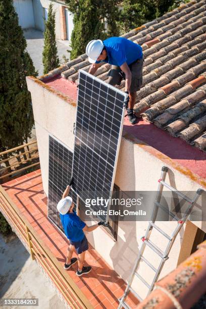 zwei arbeiter, die ein solarpanel installieren - installation art stock-fotos und bilder