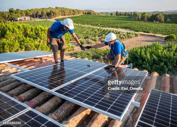 dos trabajadores instalando paneles solares - solar fotografías e imágenes de stock