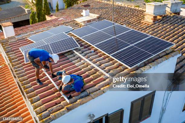 zwei arbeiter installieren sonnenkollektoren - roof tile stock-fotos und bilder