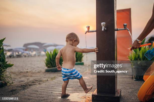 little boy washing feet on the beach - drinking fountain stock pictures, royalty-free photos & images