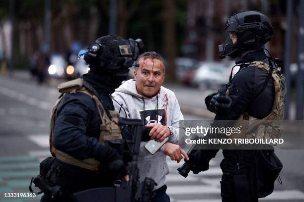 Police officer of unit RAID helps an injured man during protests in Lille, northern France, on June 29 two days after a teenager was shot dead during...