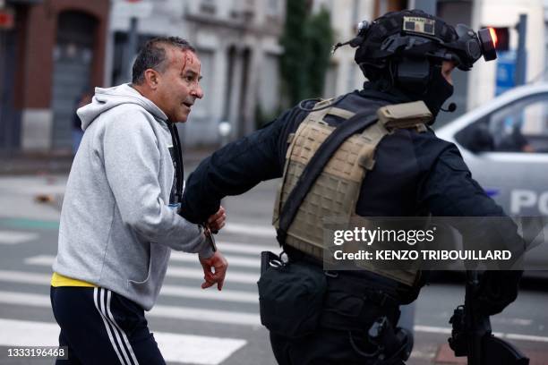 Police officer of unit RAID helps an injured man during protests in Lille, northern France, on June 29 two days after a teenager was shot dead during...