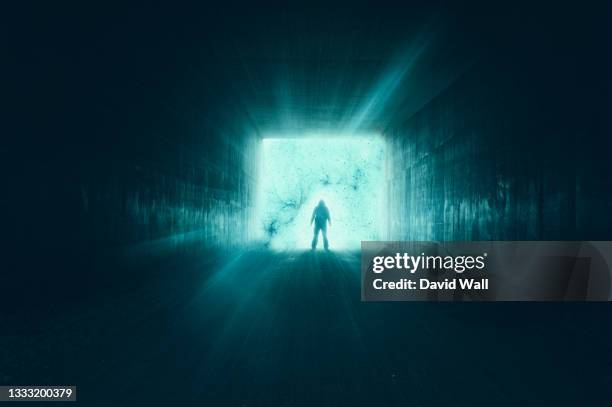 a science fiction concept of a glowing portal. with a mysterious figure silhouetted in a tunnel, with glowing lights. - grind bildbanksfoton och bilder