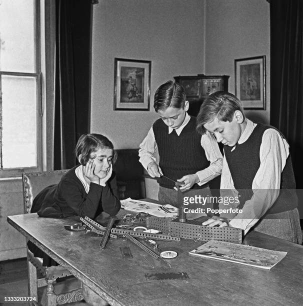 From left, Cecile, Gerard and Hubert, the children of exiled Belgian prime minister Hubert Pierlot, play with a Meccano set on a dining room table at...