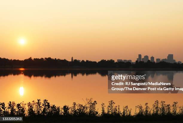 The sun rises over Sloan"u2019s Lake on poor air quality day due to smoke from California wildfires mixes with elevated ozone pollution on August 9,...