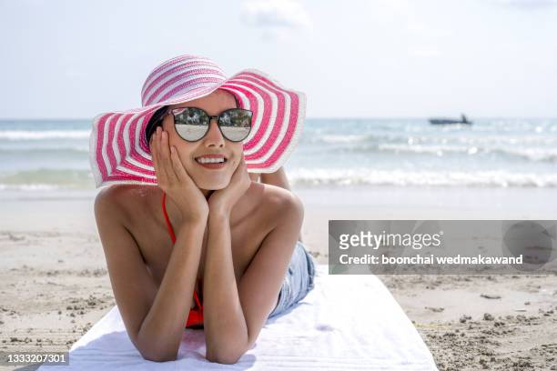 travel vacation woman on summer holiday on beach holding her summer hat sitting in the sand enjoying ocean. back view of beautiful girl in white bikini - airplane banner stock pictures, royalty-free photos & images