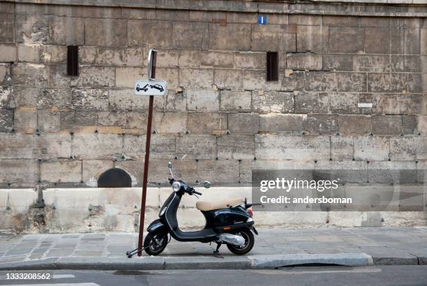 black motor scooter is locked in a traffic sign in paris - paris rocks stock pictures, royalty-free photos & images