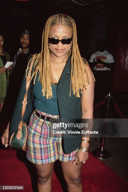 American rapper Yo-Yo, wearing a green quilted waistcoat, over a green top, with plaid shorts and sunglasses, attends an unspecified event, circa...