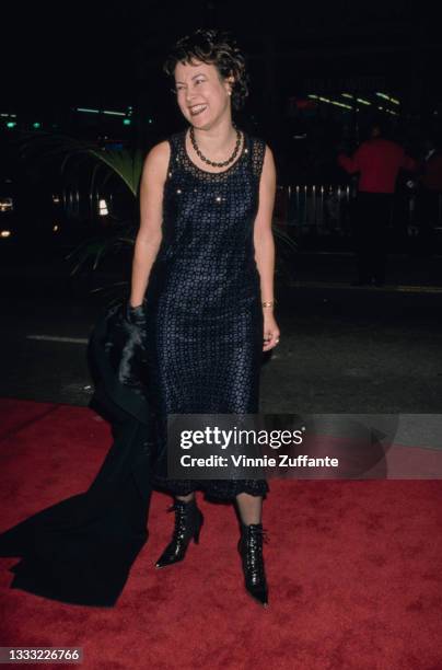 American-Canadian actress Jennifer Tilly, wearing a dark blue dress and holding a black coat, attends the Los Angeles premiere of 'Titanic' held at...