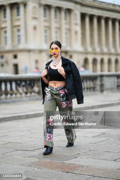 Lycia Lamini wears orange with pearls sunglasses, black and white large Japanese character pendant earrings, silver and rhinestones chain necklace, a...