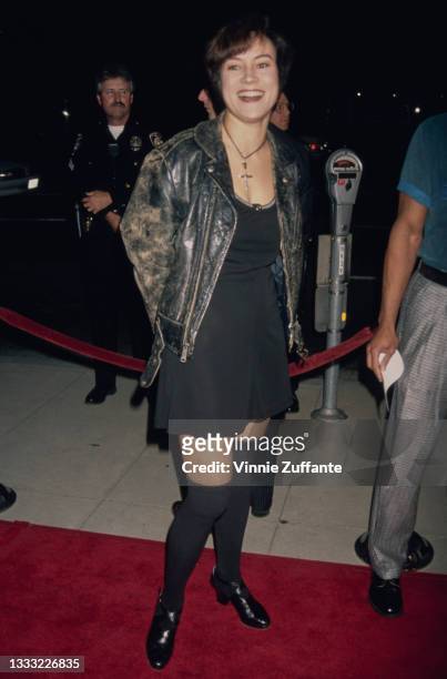 American-Canadian actress Jennifer Tilly, wearing a leather jacket over a black mini dress, attends the Beverly Hills premiere of 'Threesome' held at...