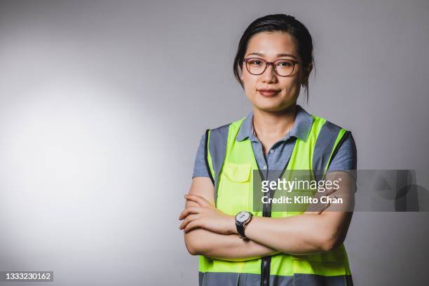 portrait of asian female architect/construction worker standing with arms crossed - builder standing isolated stock-fotos und bilder