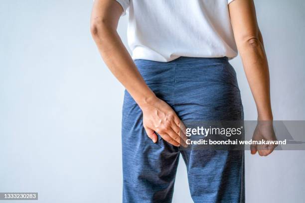 woman hand holding her bottom because having abdominal pain and hemorrhoids, health care concept. - woman hemorrhoids stock pictures, royalty-free photos & images