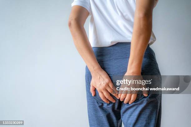 woman hand holding her bottom because having abdominal pain and hemorrhoids, health care concept. - fart stock-fotos und bilder