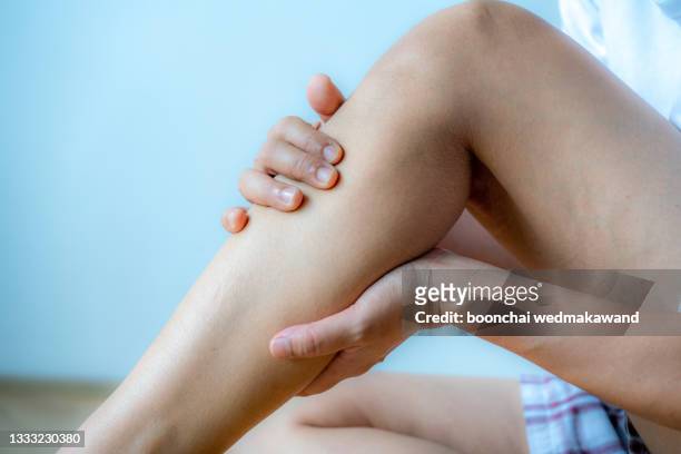 young woman suffering from pain in leg at home - beine stock-fotos und bilder