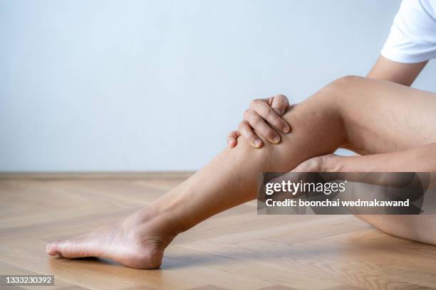 young woman suffering from pain in leg at home - svullen bildbanksfoton och bilder