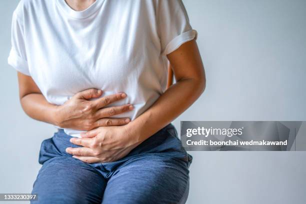 woman with stomach ache, menstrual period cramp, abdominal pain, food poisoning - brechreiz stock-fotos und bilder