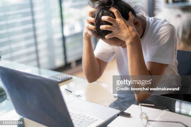 tired young business woman or student with a headache using laptop at the home office. - mood stream stock pictures, royalty-free photos & images