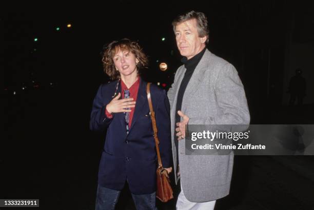 Bonnie Bedelia, wearing a blue blazer over a red shirt, with a tan leather shoulder bag, and American actor Paul Gleason , wearing a grey blazer over...