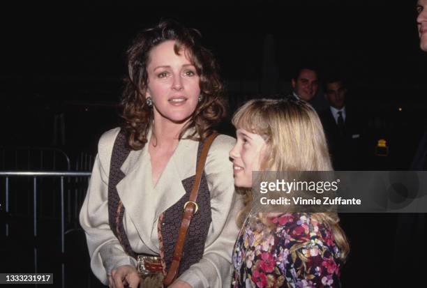 American actress Bonnie Bedelia wearing a silk blouse with a waistcoat, and an unspecified young female companion, attend an unspecified event,...
