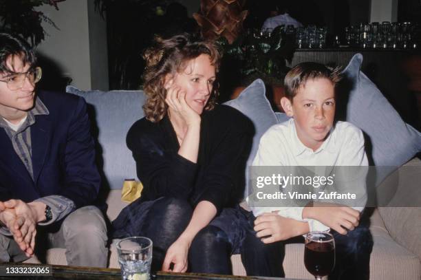 American actress Bonnie Bedelia sitting with her sons, Uri and Jonah, with drinks on the table before them at an unspecified event, location...